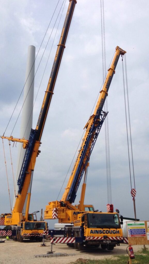 Mobile crane in operation at a construction site, lifting materials with workers in safety gear.